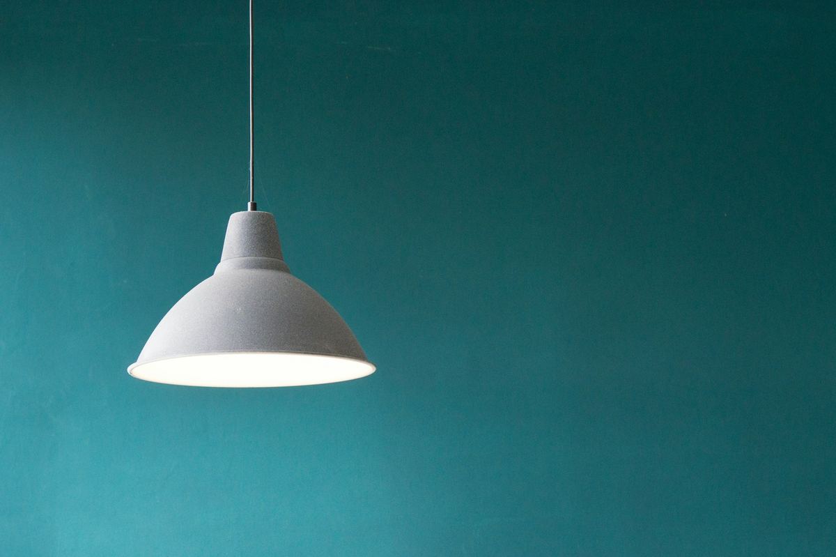 A single lamp glowing brightly against a dark wall — light overcoming darkness